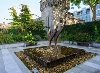  TWO STYLISED FIGURES WITH THE OLYMPIC FLAME - SPECIAL OLYMPICS MEMORIAL BY JOHN BEHAN 